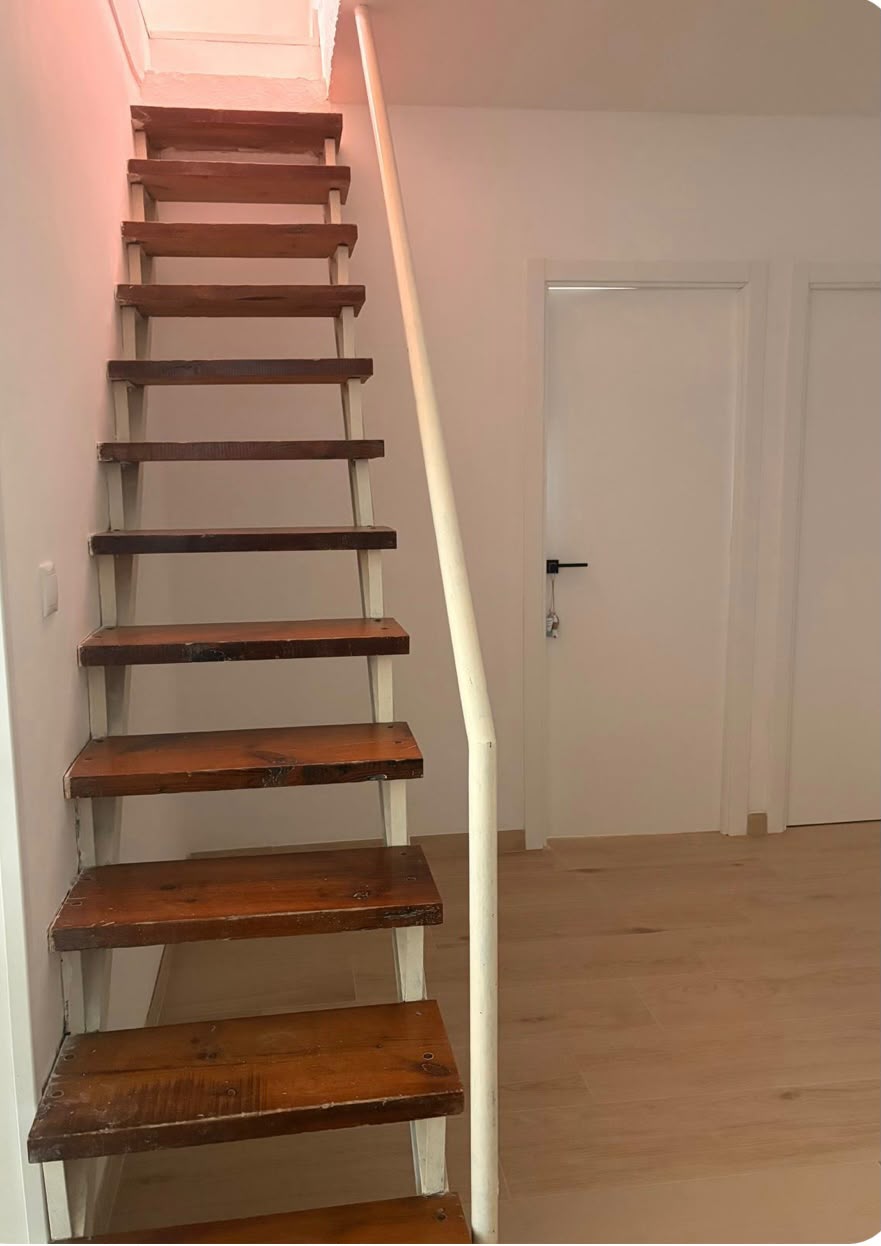 Escalera de madera de acceso a la planta superior