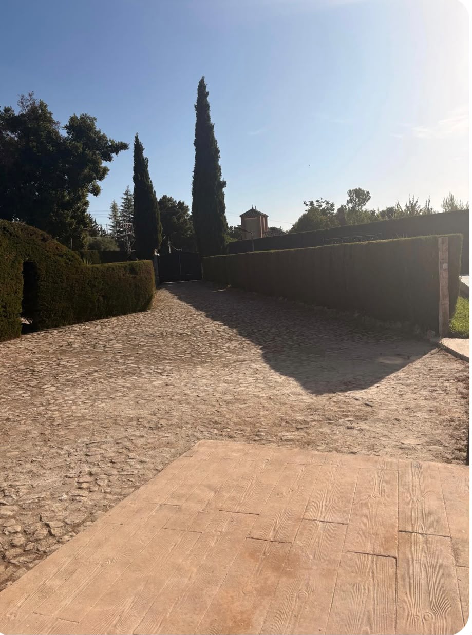 Entrada empedrada con seto y aparcamiento